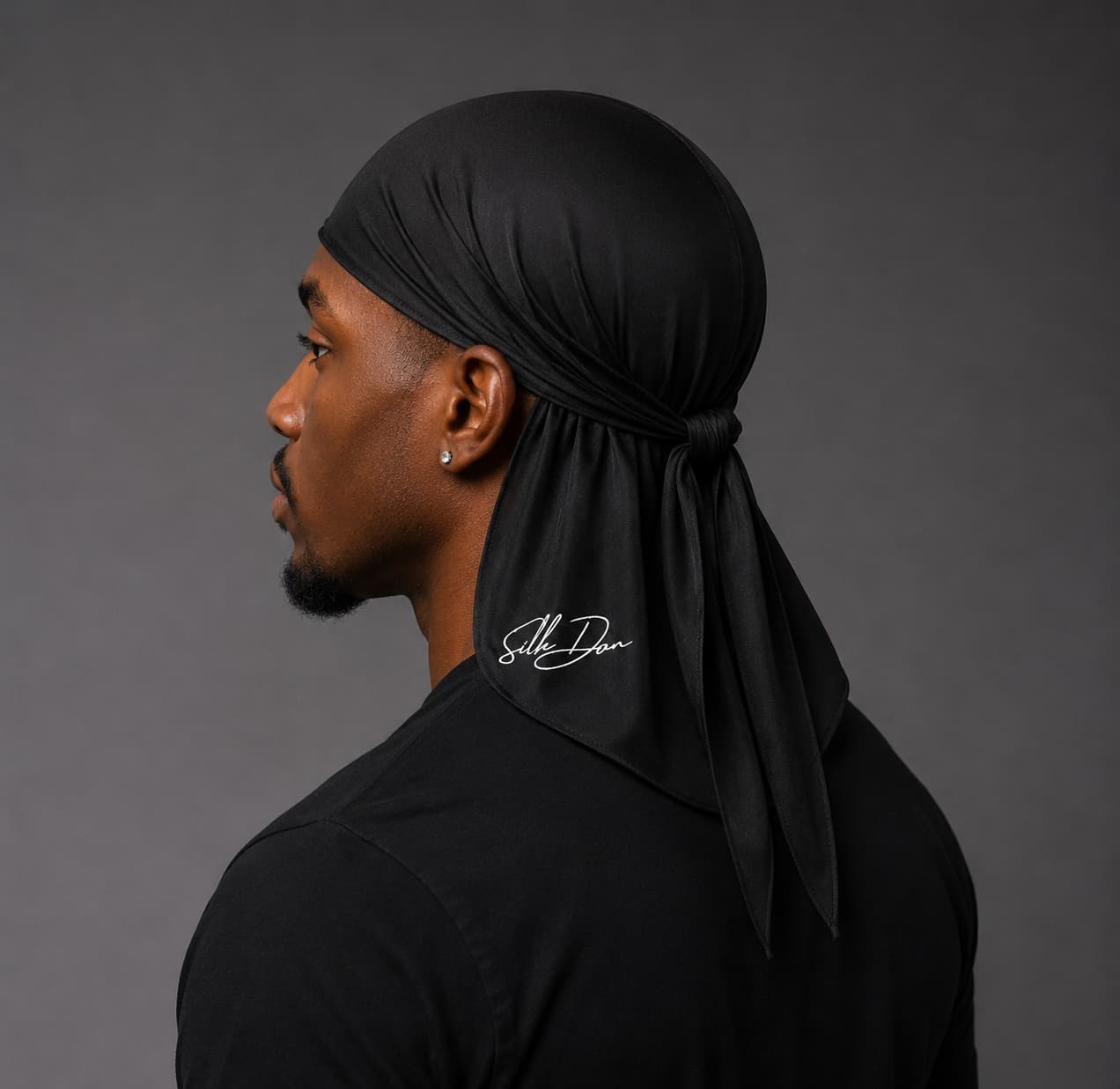 Man wearing a black durag with a SilkDon logo on a gray background